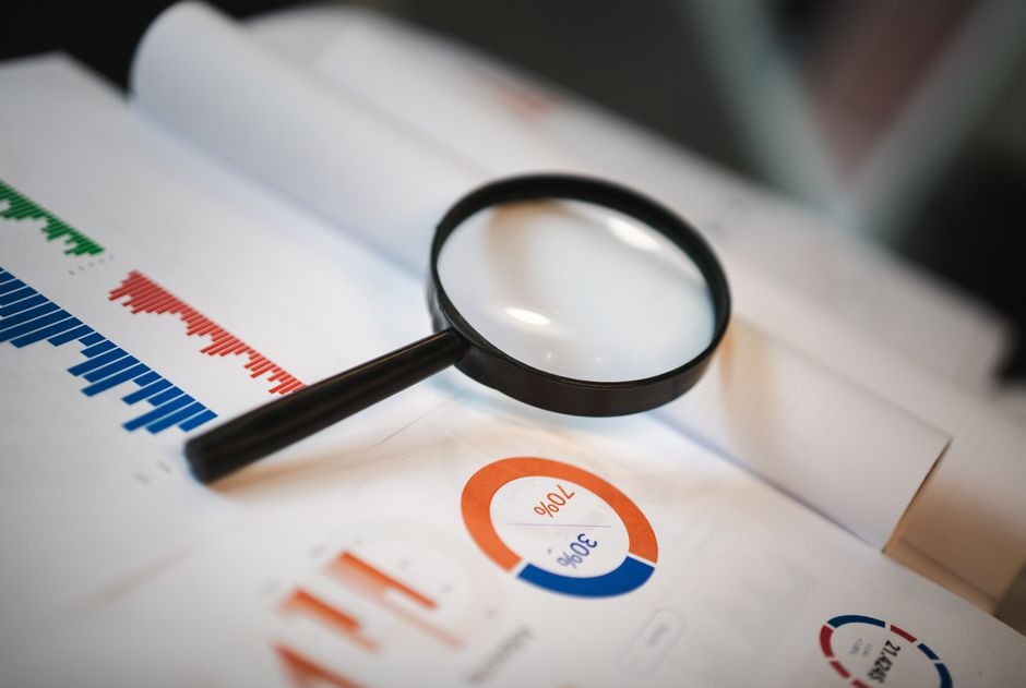 magnifying glass resting on printed reports